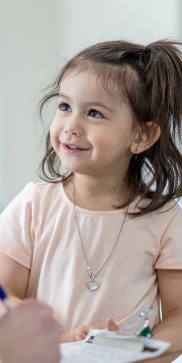 Child smiling at her pediatrician in a medical appointment.